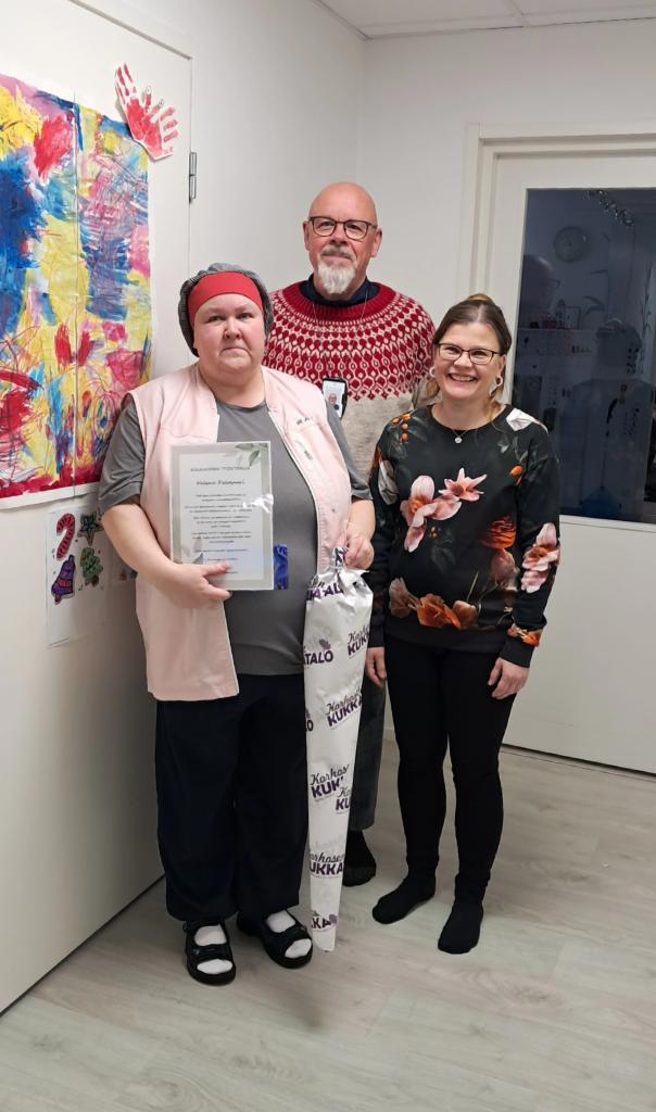 Kuvassa kolme henkilöä hymyilee kameralle.