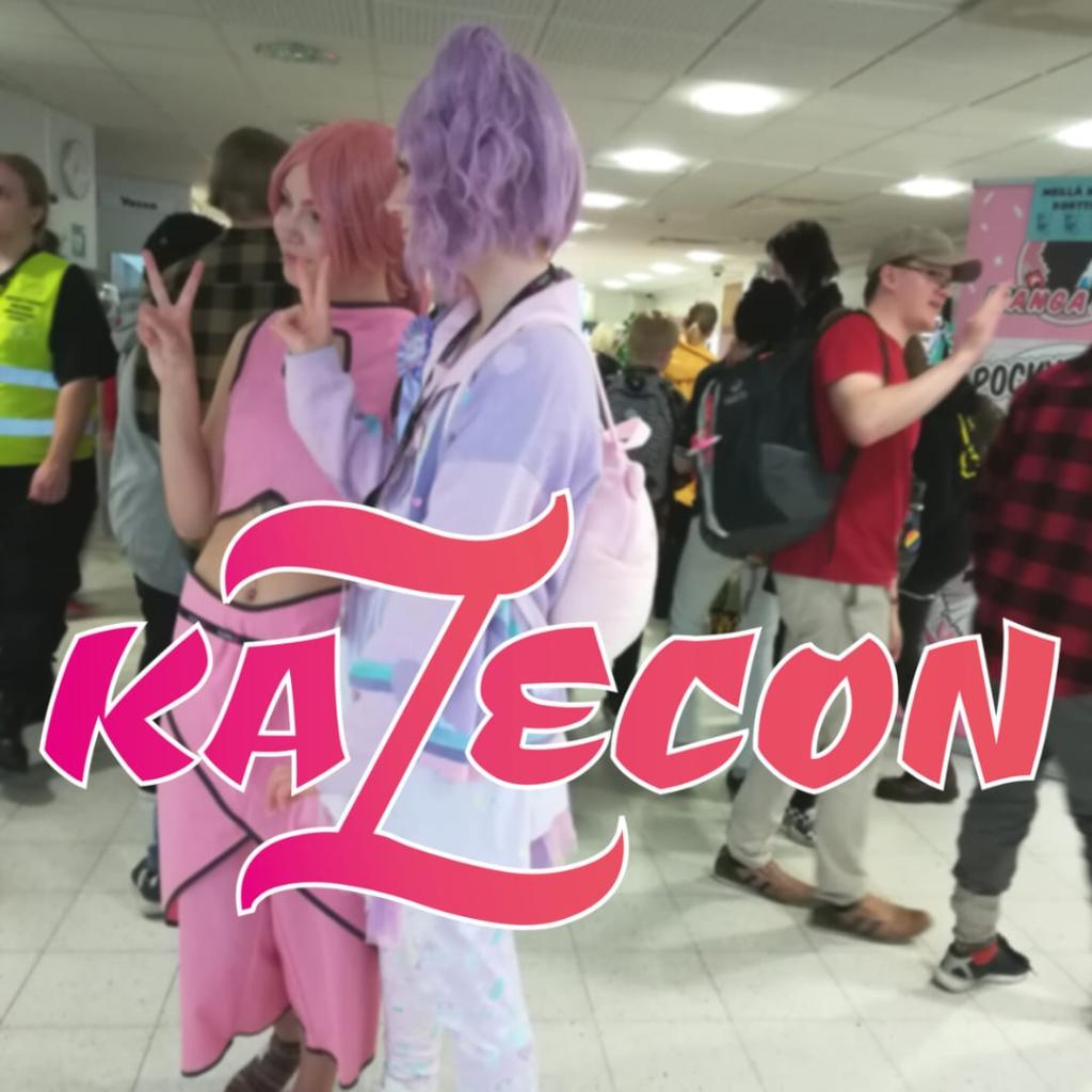 Kuva: Nuorisopalvelut Vaalenapunaisissa ja violeteissa cosplay-asuissa kaksi ihmistä poseeraamassa kameralle. Taustalla ihmisiä käytävällä. Päällä pinkki Kazecon -logo