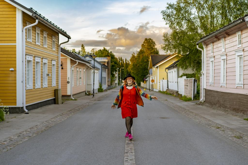 Nainen kävelemässä kadulla puutaloalueella.