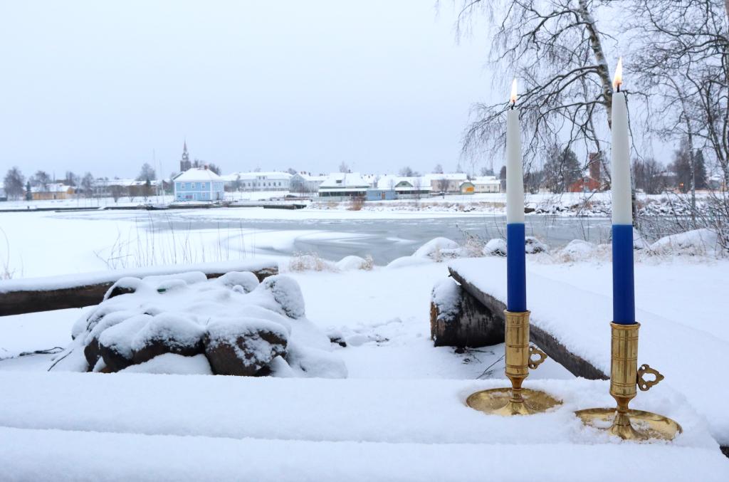 Raahen maisemassa kaksi adventtikynttilää lumella.