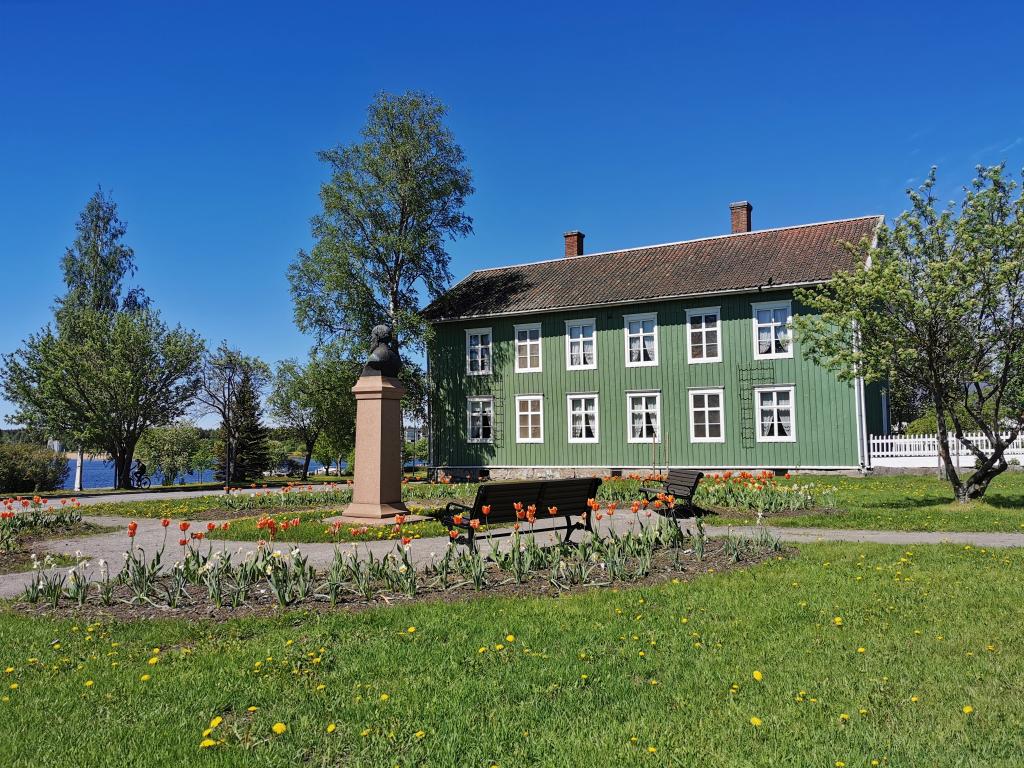 Myhrbergin puisto. Kuva: Raahen kaupunki. Vanha vihreä kaksikerroksinen puutalo puiston laidalla.