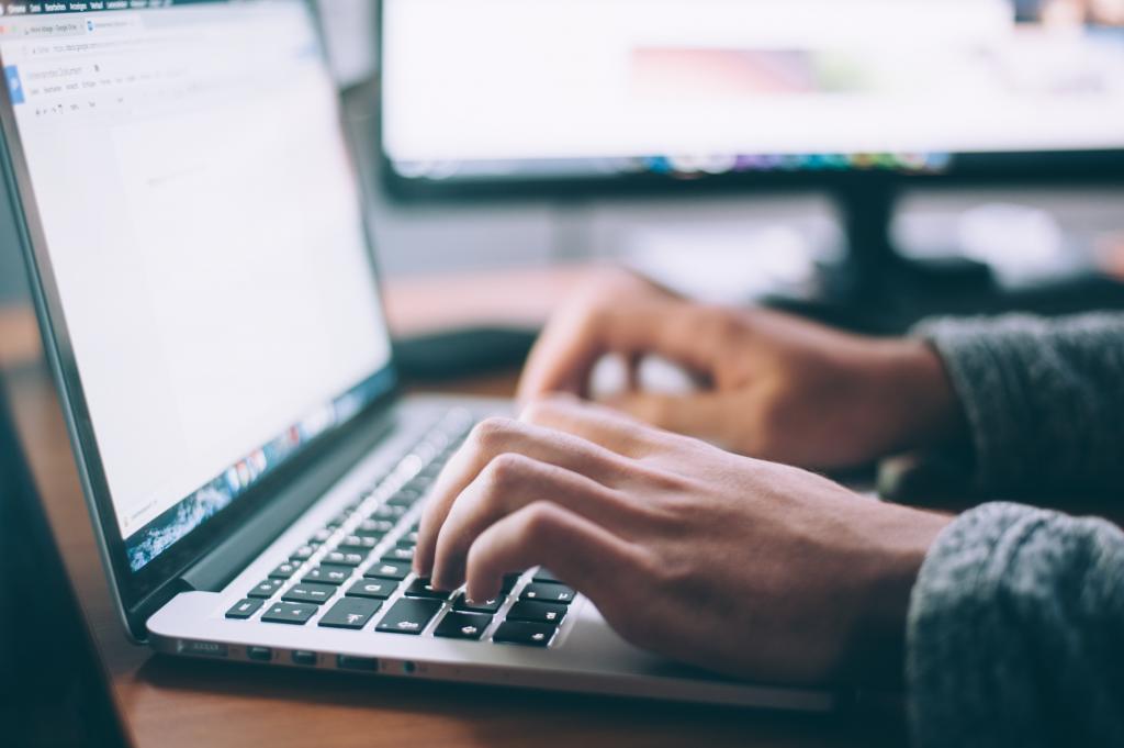 Sähköinen avustushaku tuo joustavuutta hakuprosessiin. Kuva: Glenn Carstens Peters, Unsplash. Henkilö kirjoittaa kannettavalla tietokoneella.