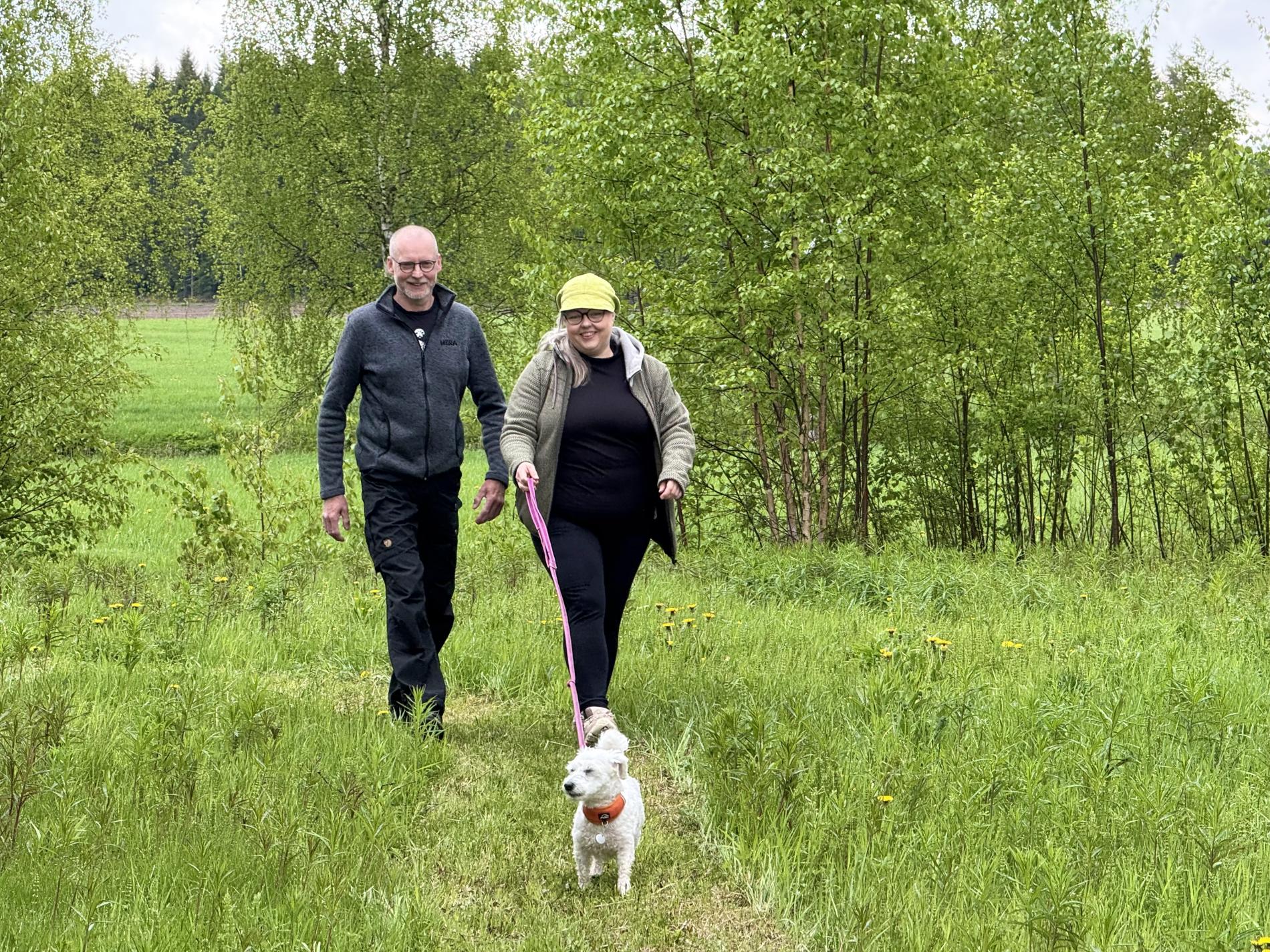 Jarkko, Päivi ja Essi-koira kävelevät tiluksillaan.