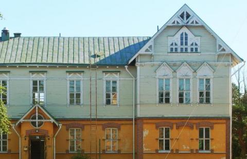 En gammal tvåvåningsbyggnad med olika färg och material på varje våningsplan.