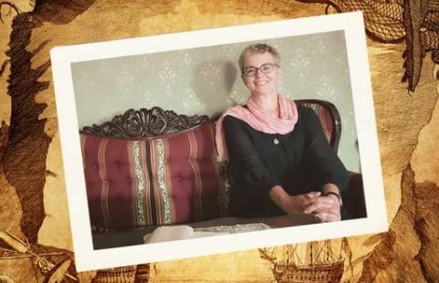 Kuvassa hymyilevä ihminen, joka istuu sohvalla.