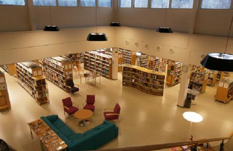 Bibliotekets lekplats med en stor mjuk leksak och en dekorativ lässtol.