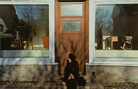 Kuvassa Laura Juntunen istuu vanhan rakennuksen portailla. Kuvaaja Sina Sarpola