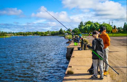 Two boys fishing by the shore.