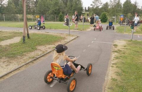 Lapsi ajaa oranssilla polkuautolla.