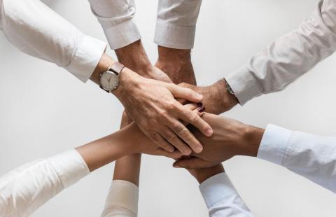 Eight people holding their hands on top of one another.