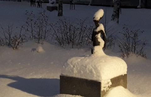 Veistospuiston valaistu patsas lumen peittämänä.