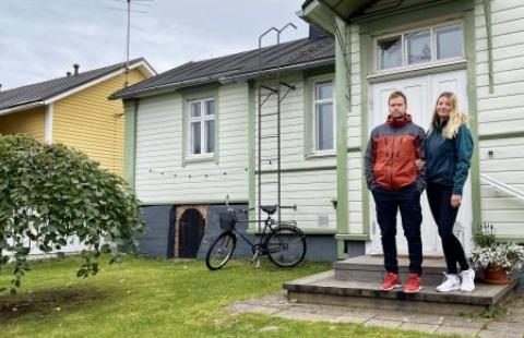 A man and a woman standing on the steps of a wooden house in the old town. 