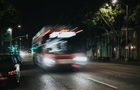 Bus at night on black road.