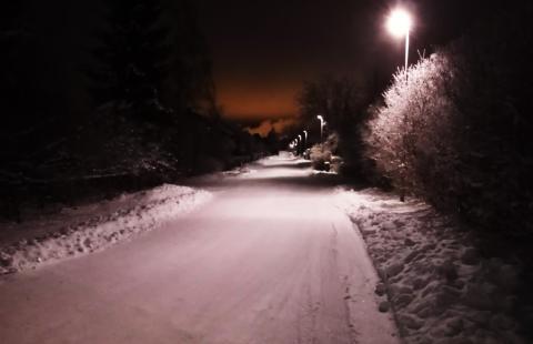 Talvinen tie, jota valaisee katuvalot.