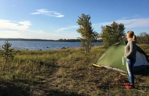 Kuva: Tiina Partasen kotialbumi. Nainen seisomassa teltan edessä saaressa.
