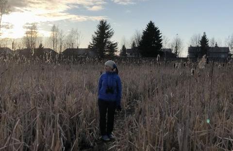 Kuva: Tiina Partasen kotialbumi. Nainen pellolla kiikarit kaulassaan.