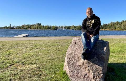 A man sitting on a rock by the sea.