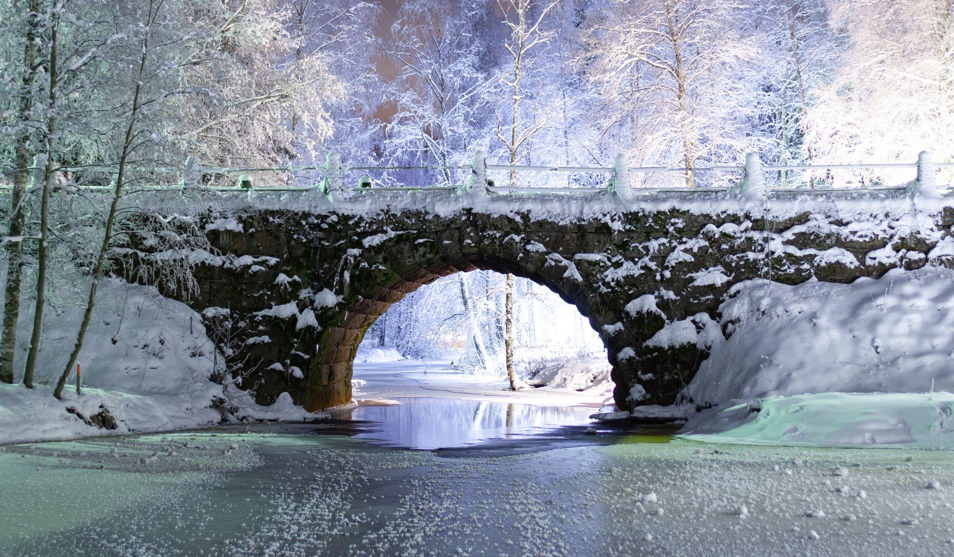 Каменный арочный мост в Паттийоки в снежном пейзаже.