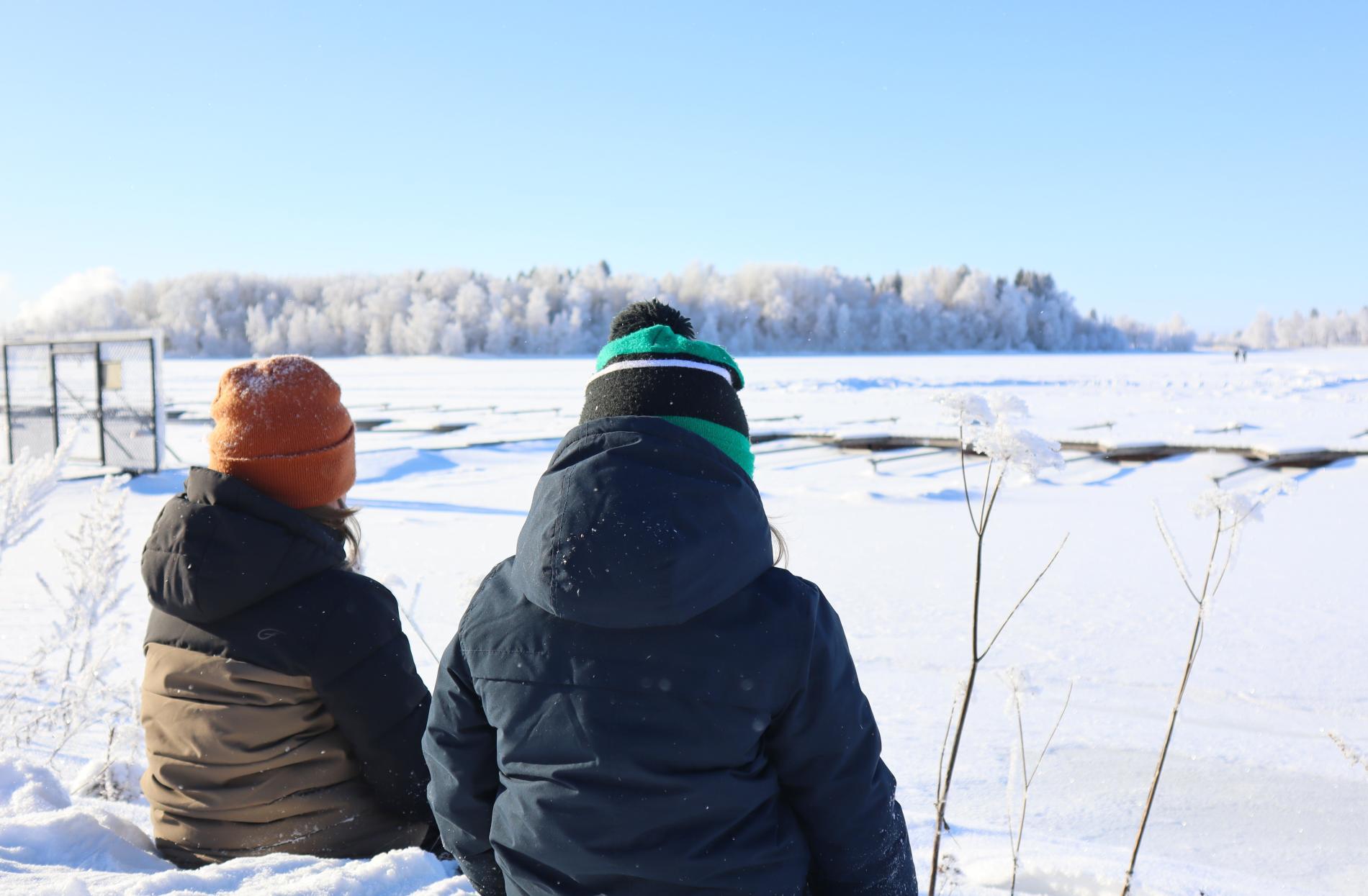 Lapset istuvat talvella Pikkulahdella.