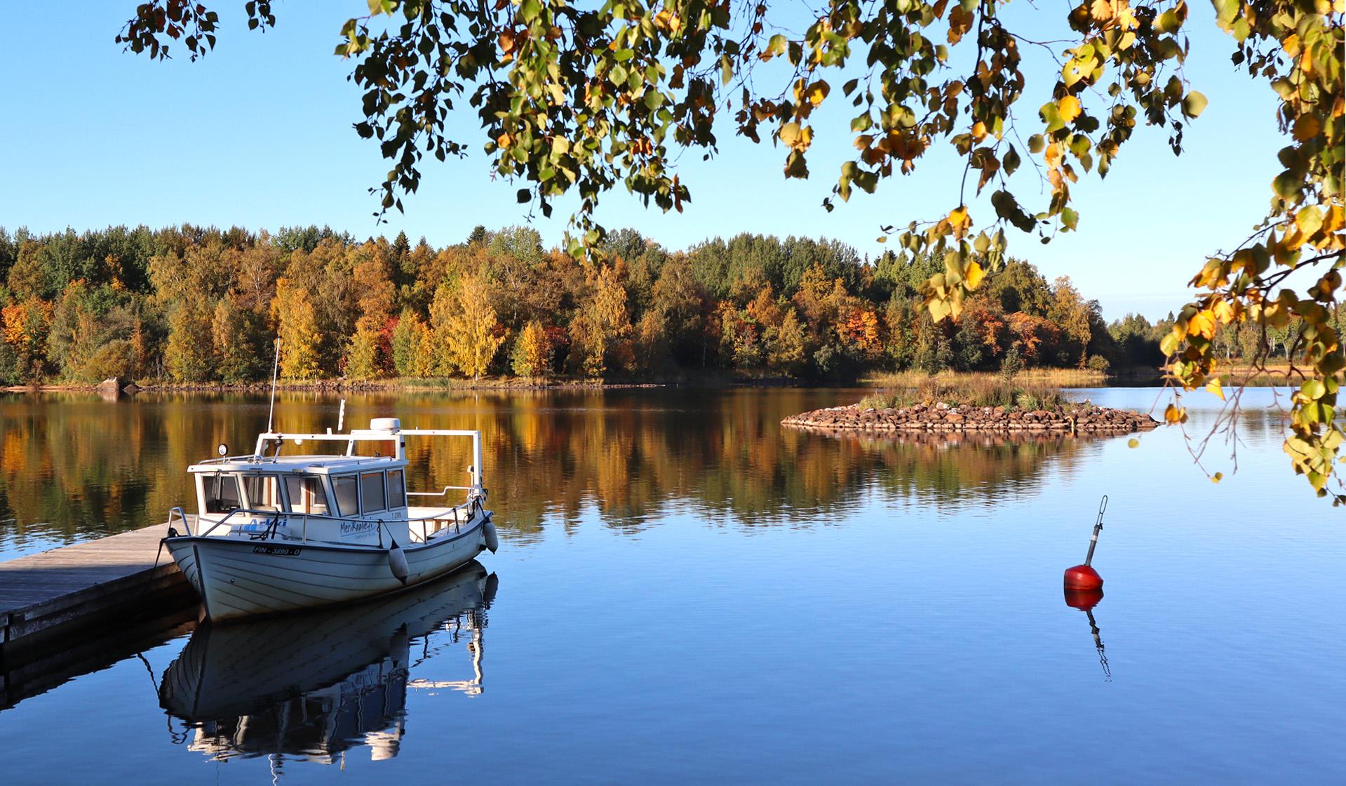 Лодка и док на берегу моря. Осенний пейзаж на заднем плане.