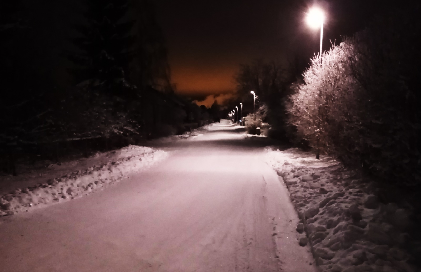 Talvinen tie, jota valaisevat katuvalot.