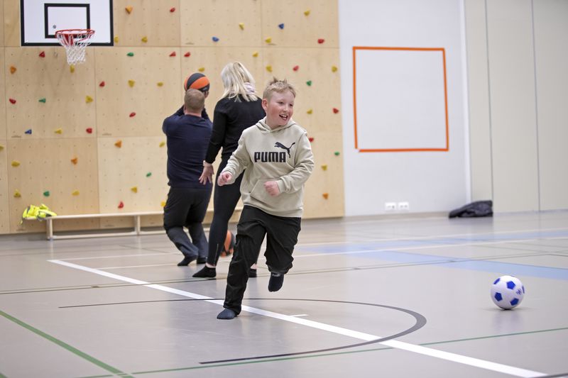 Perhe liikunta-aktiviteettien äärellä liikuntasalissa.