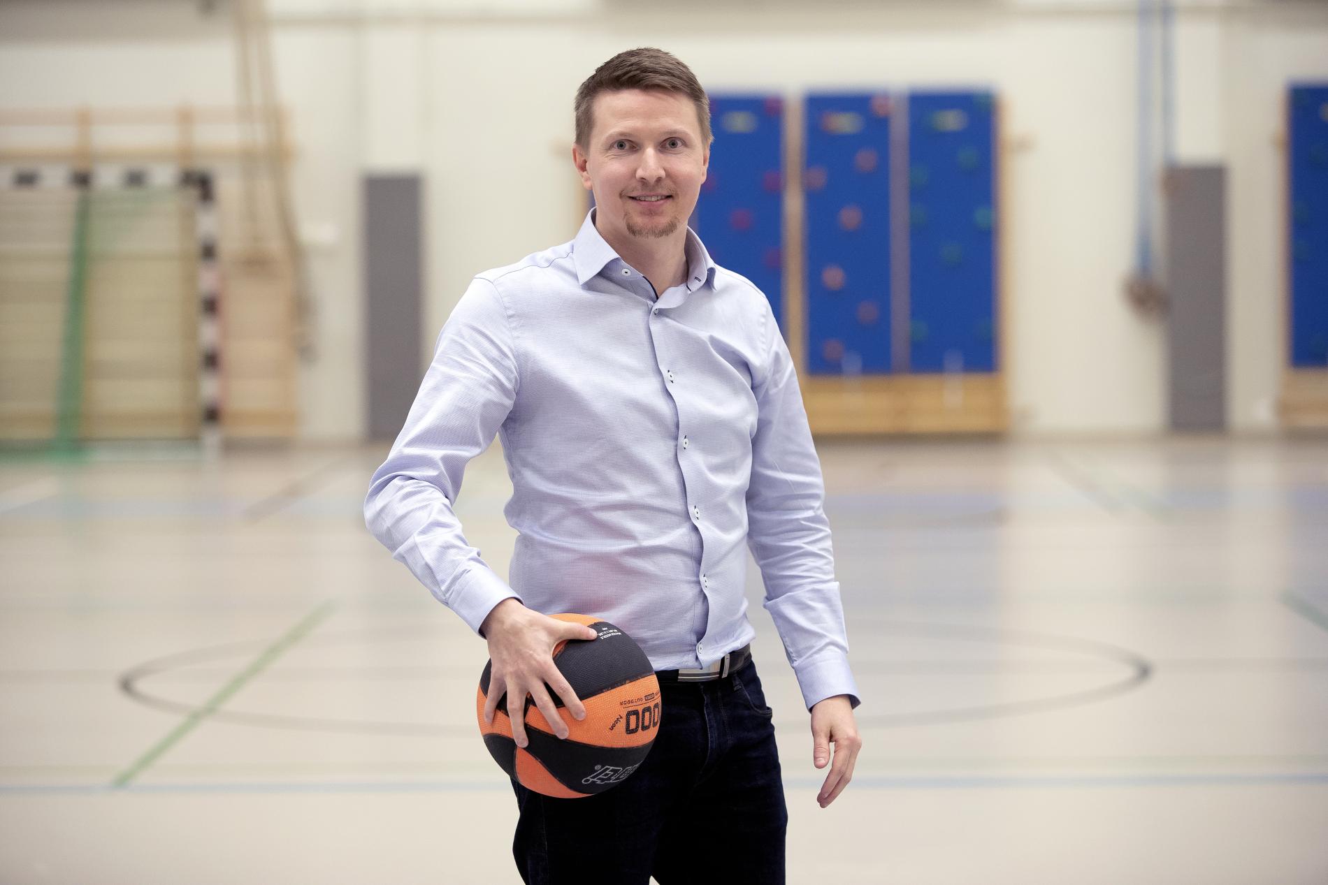 Head of Sports Services in the gym with a basketball in his hand.