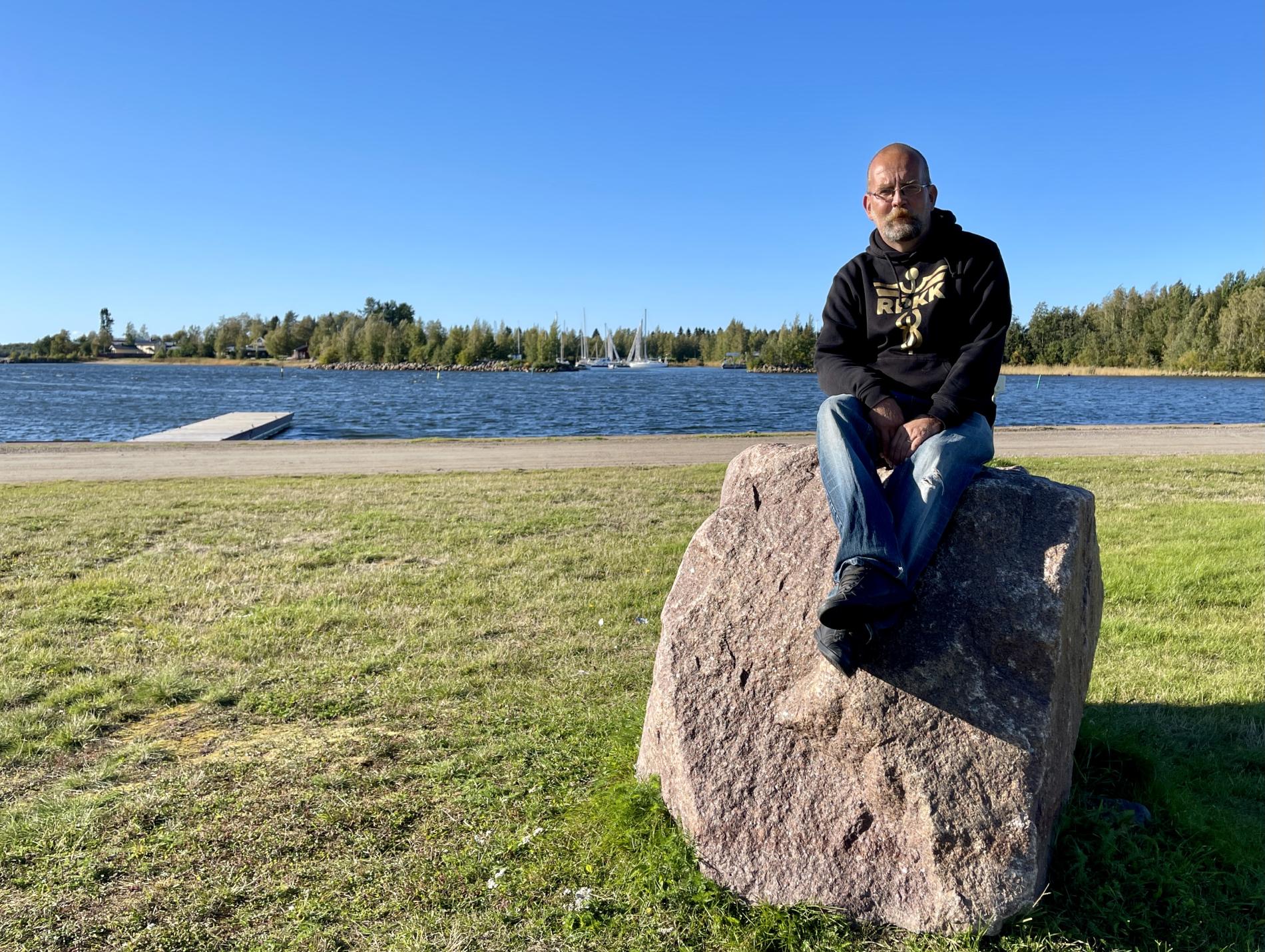 A man sitting on a rock by the sea.