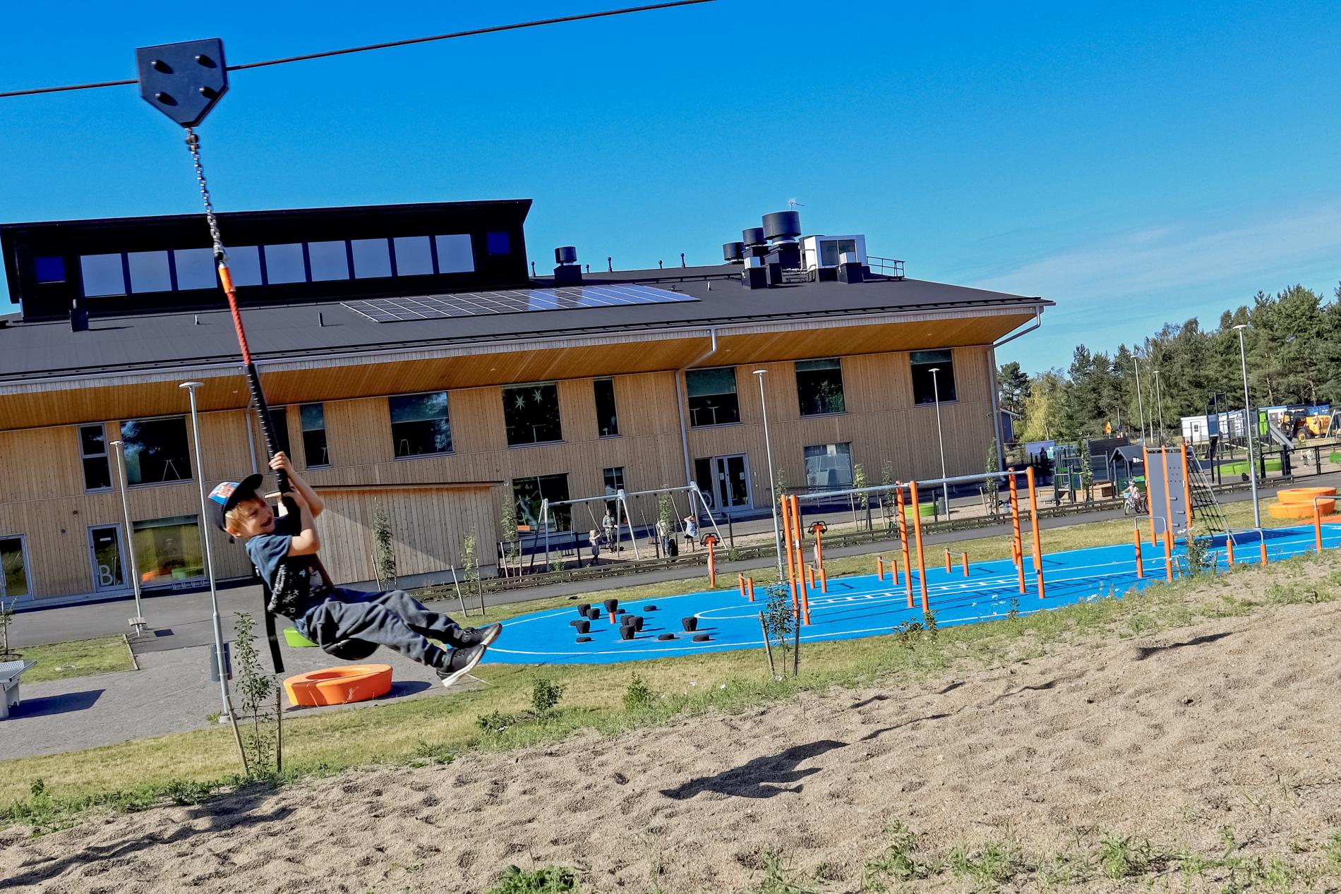 Lapsi leikkimässä vaijeriliukua Saloisten koulukeskuksen pihalla.