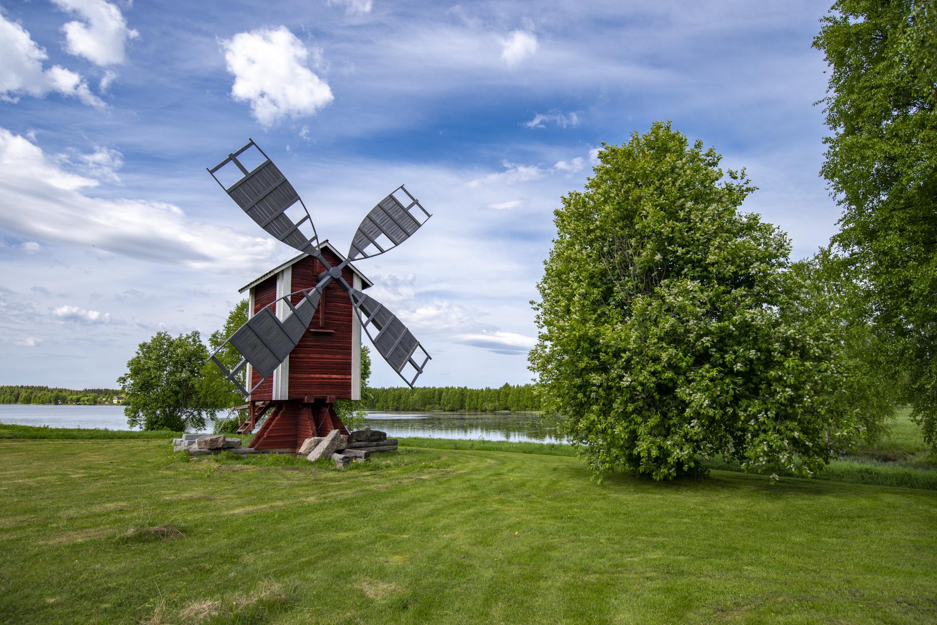 Puinen tuulimylly kesäisen vihreän Kirkkojärven rannalla.