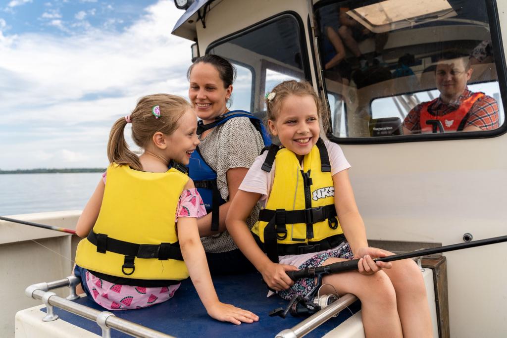 Kaksi hymyilevää lasta istuu veneessä pelastusliivit päällä.